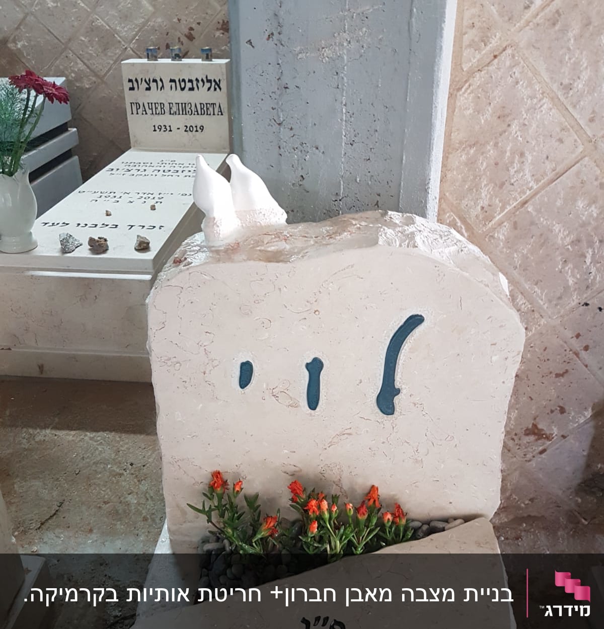 מצבות עם כיתוב בעברית ופרחים כתומים